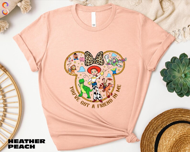 A pink t-shirt with a cartoon character design and text, along with some other items such as a straw hat and a potted plant.