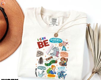 Peut inclure: T-shirt ivoire avec l'inscription "I CAN BE" en rouge et vert. Le motif présente des illustrations colorées d'une souris, d'un éléphant, d'une chenille et d'un poisson, avec les mots "Adventurous", "Calm" et "Kind".