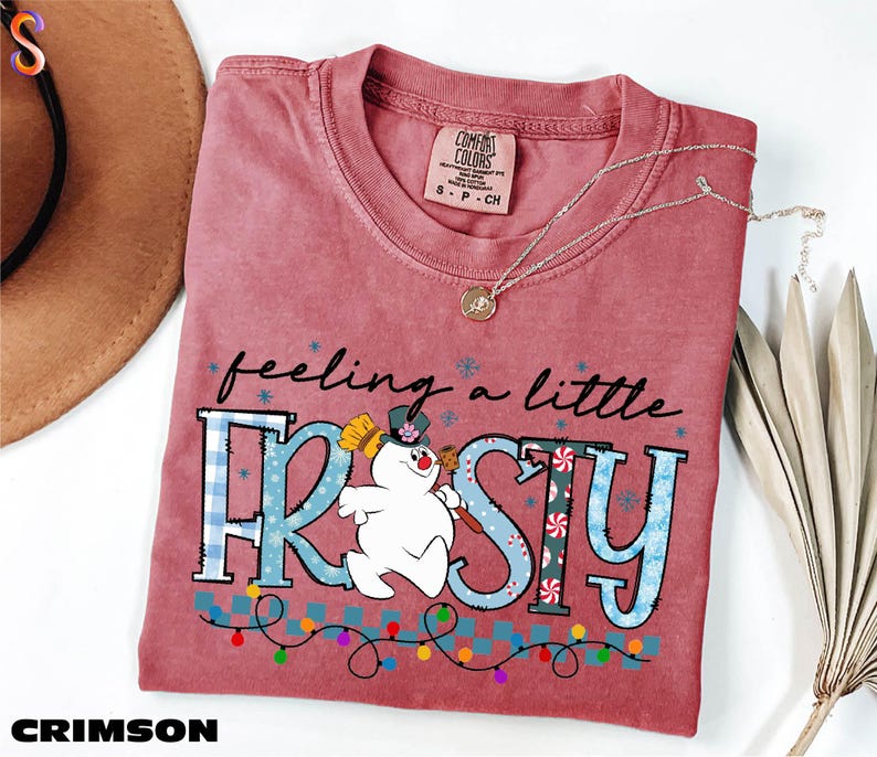 A red t-shirt with a cartoon snowman and the text "feeling a little FROSTY" printed on it, along with a necklace and a hat.