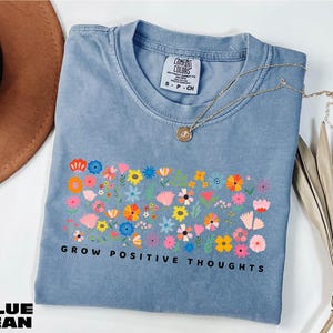a blue t - shirt that says grow positive thoughts