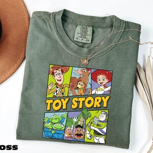 A green t-shirt with a colorful graphic of characters from the Toy Story movie, including Woody, Buzz Lightyear, and other beloved characters, along with the text "TOY STORY".