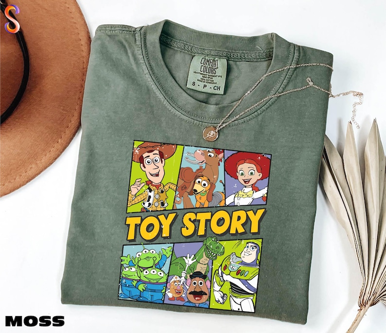 A green t-shirt with a colorful graphic of characters from the Toy Story movie, including Woody, Buzz Lightyear, and other beloved characters, along with the text "TOY STORY".