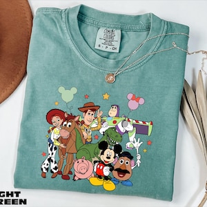 A light blue t-shirt with a colorful graphic of characters from the Toy Story movie, including Woody, Buzz Lightyear, and other beloved characters.