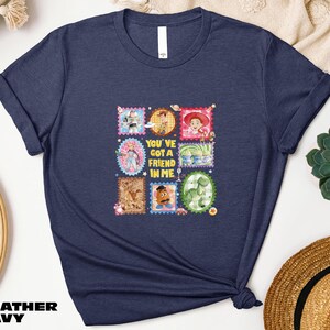 A navy blue t-shirt with a collage of colorful images and text, including characters from the Toy Story franchise, along with the text "You've got a friend in me".