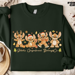 A green sweater with a Christmas-themed design featuring four cartoon characters, including Stitchie, Gingerbread, Baking, and Stitchie, along with the text "Stitchie, Gingerbread, Baking, Stitchie".