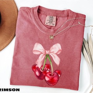 a pink shirt with a bow and cherries on it