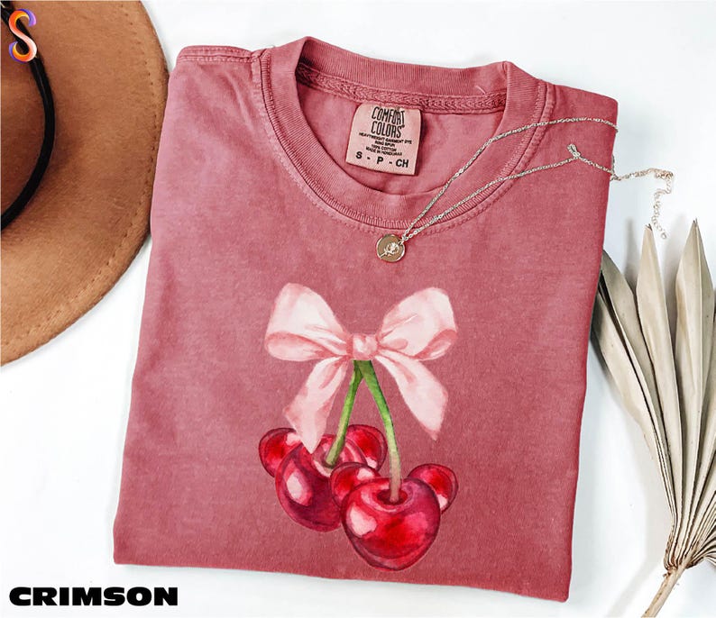 a pink shirt with a bow and cherries on it