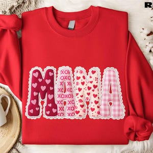 A red sweatshirt with the word "Mama" printed on it, surrounded by decorative heart shapes in various colors.