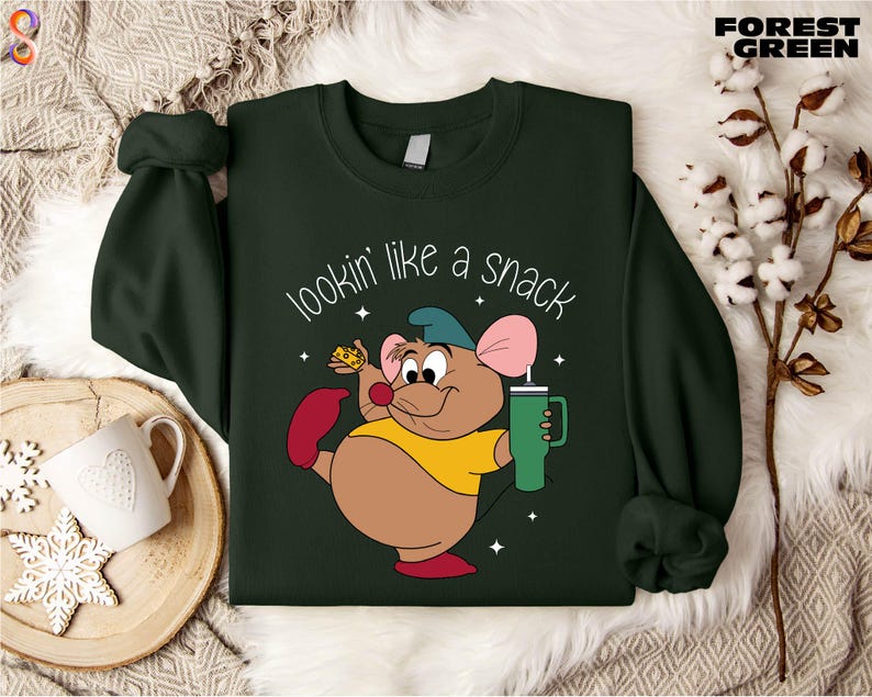 K&ouml;nnte beinhalten: Dunkelgr&uuml;nes Sweatshirt mit einer Cartoon-Maus, die ein Getr&auml;nk und ein St&uuml;ck K&auml;se h&auml;lt. Der Text "lookin' like a snack" ist in Wei&szlig; geschrieben. Das Sweatshirt hat lange &Auml;rmel und einen Rundhalsausschnitt.
