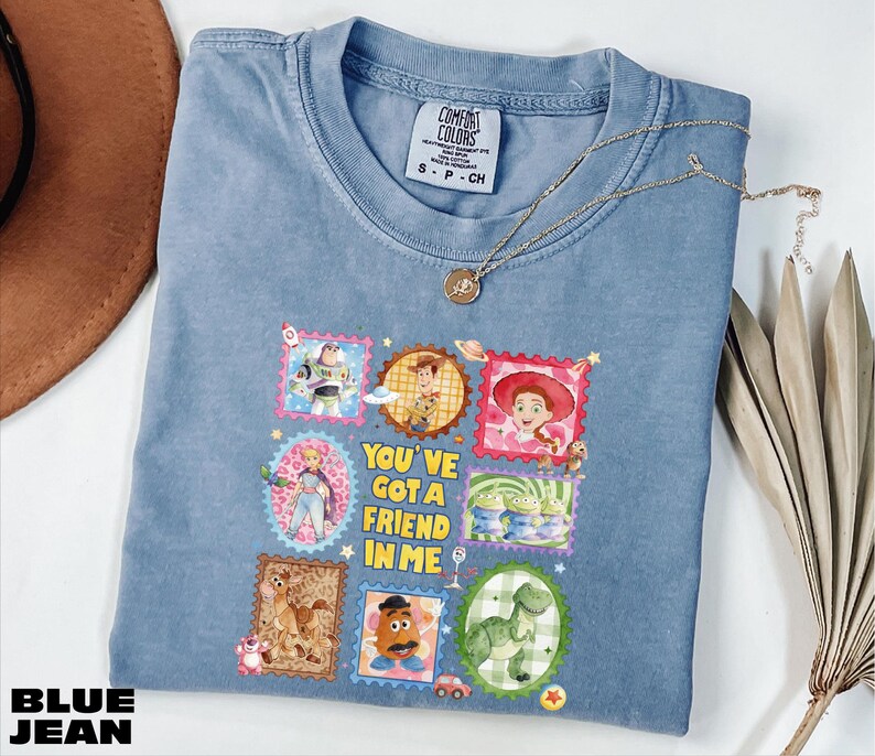 A blue denim t-shirt with a colorful graphic design featuring characters from the Toy Story movie, along with the text "You've got a friend in me".