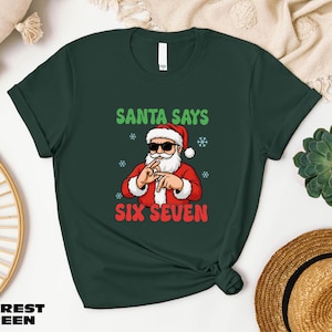 A green t-shirt with a graphic of Santa Claus and the text "SANTA SAYS SIX SEVEN" printed on it, along with a straw hat and some decorative items.