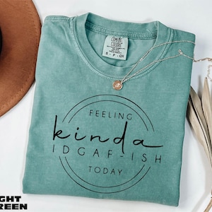 A turquoise t-shirt with the text "Feeling Kinda Idgafish Today" printed on it, along with a necklace and a brown hat.