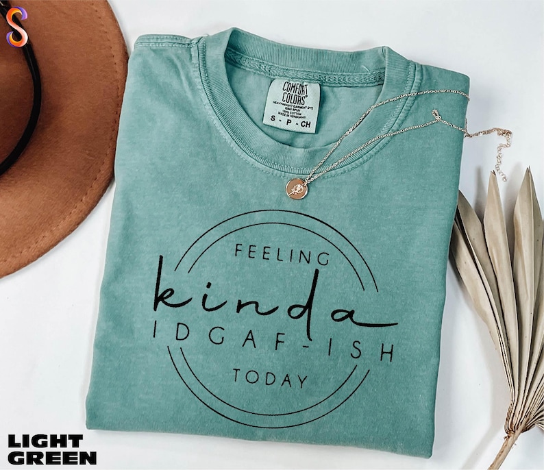 A turquoise t-shirt with the text "Feeling Kinda Idgafish Today" printed on it, along with a necklace and a brown hat.