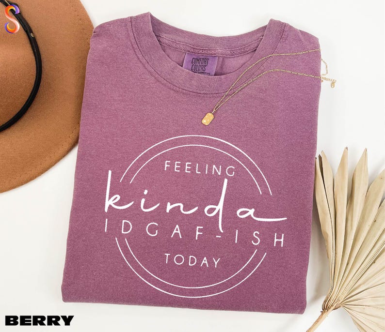 a purple t-shirt with a white text design that says "Feeling kinda idgafish today", along with a brown hat and a fan.