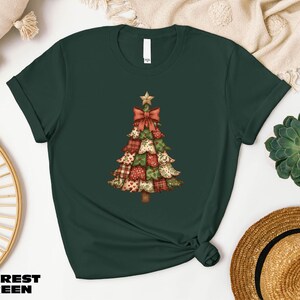 A green t-shirt with a Christmas tree design printed on it, along with other items such as a hat, a woven basket, and a potted plant.