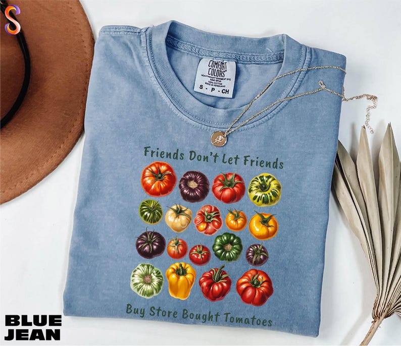 A blue denim t-shirt with a graphic of various colored tomatoes, along with the text "Friends Don't Let Friends" and "Buy Store Bought Tomatoes".