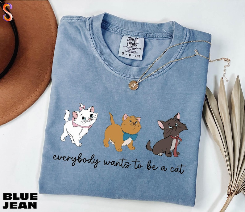 a blue t - shirt with three cats on it