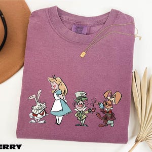 a purple t - shirt with a picture of alice and the rabbit on it