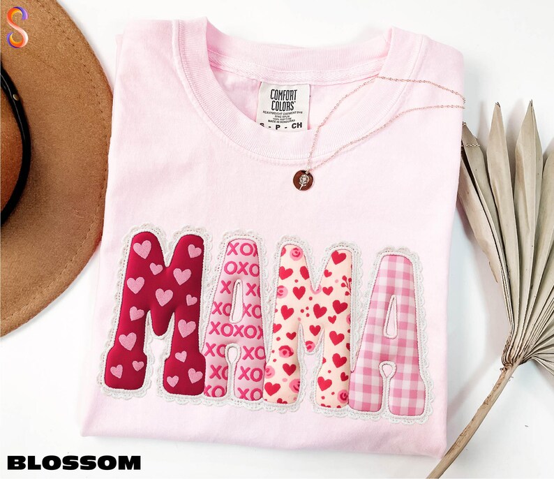 A pink t-shirt with the word "MAMA" printed on it, along with a necklace and a hat.