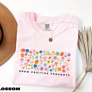a pink shirt with flowers and a hat next to it