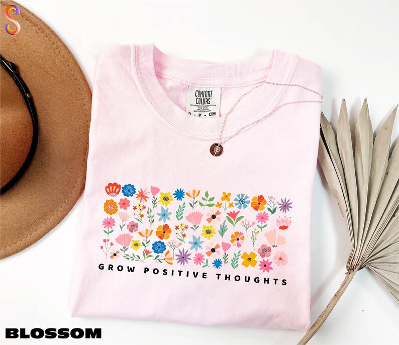 a pink shirt with flowers and a hat next to it