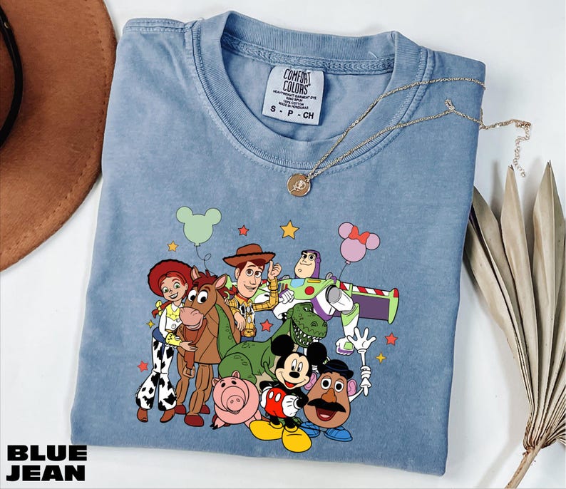 A blue t-shirt with a cartoon character design featuring characters from the Toy Story franchise, including Woody, Buzz Lightyear, and other beloved characters.