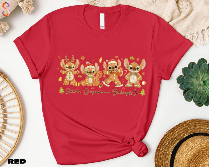 A red t-shirt with a graphic design featuring four cartoon characters, likely from the Disney movie Lilo & Stitch, along with the text "Stitch's Gingerbread Co."