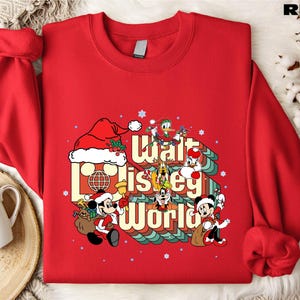 A red sweater with a Disney-themed graphic design, including Mickey Mouse and other Disney characters, along with the text "Disney World".