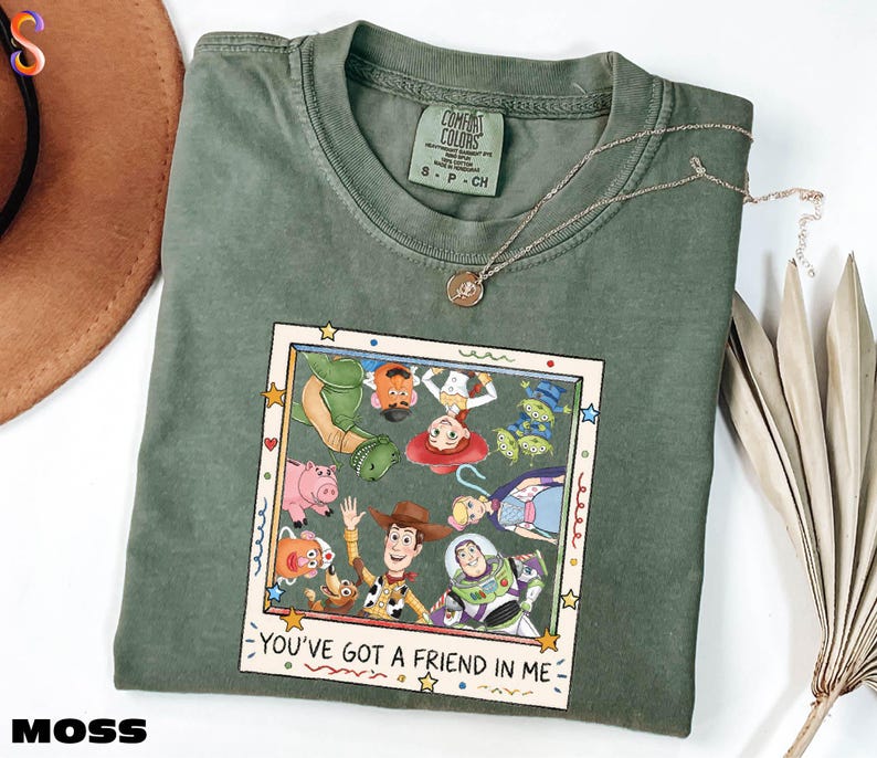 A green t-shirt with a graphic of characters from the Toy Story movie, including Woody, Buzz Lightyear, and other beloved characters, along with the text "You've Got a Friend in Me".