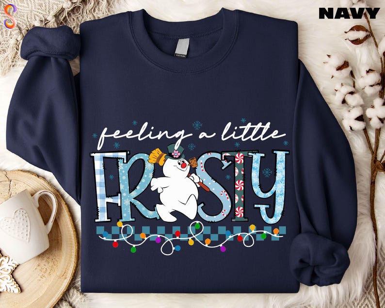 A navy blue sweatshirt with a snowman graphic and the text "feeling a little FRISKY" printed on it.