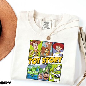 A white t-shirt with a colorful graphic of characters from the Toy Story movie, including Woody, Buzz Lightyear, and other beloved characters.