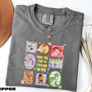 A gray t-shirt with a colorful graphic design featuring characters from the Toy Story movie, along with the text "You've Got a Friend in Me".