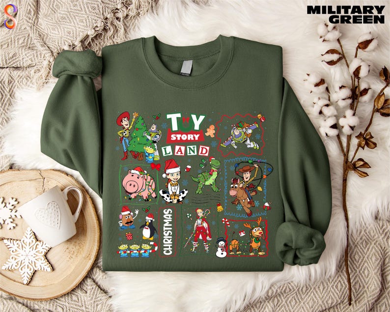 A green sweatshirt with a collage of various characters from the Toy Story franchise, including Woody, Buzz Lightyear, and other beloved characters, along with Christmas-themed elements.