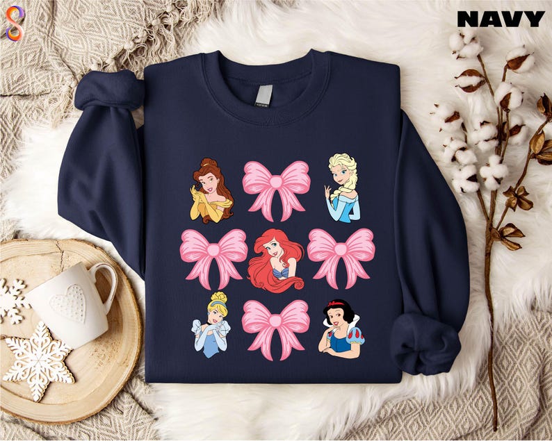 a sweater with princesses on it next to a cup of coffee