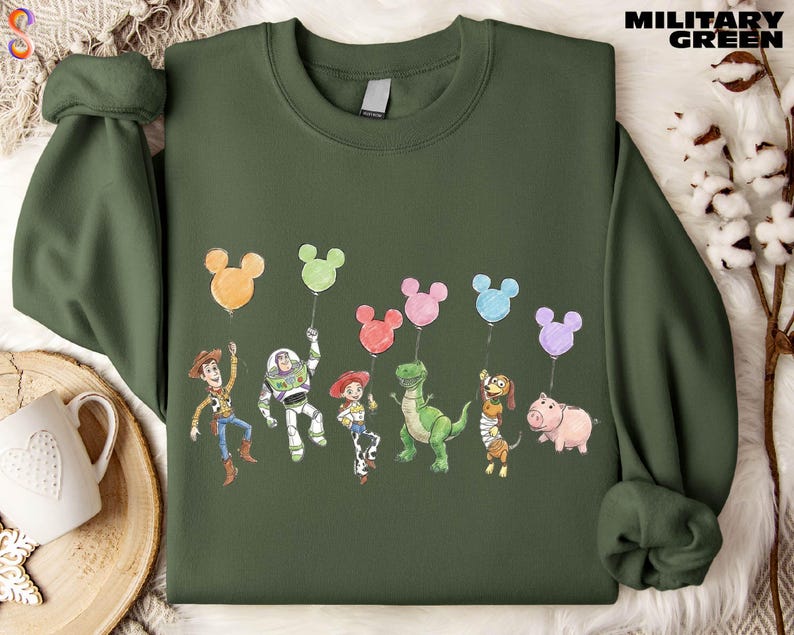 A green sweatshirt with a graphic design featuring characters from the Toy Story movie, including Woody, Buzz Lightyear, Timmy, and other beloved characters.