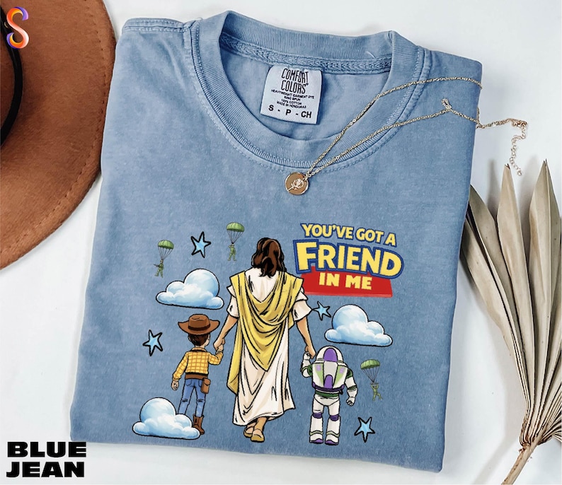 A blue t-shirt with a graphic design depicting a person holding a child and a character from the Toy Story franchise, along with the text "You've got a FRIEND in me".