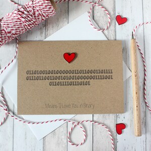 May include: A brown card with a red heart on the top left corner. The card has a message in binary code that reads "011010010100000111001110001101111 011101110011010100110000001111001 01101111011111101110101". Below the binary code is the text "Means I Love You in Binary".