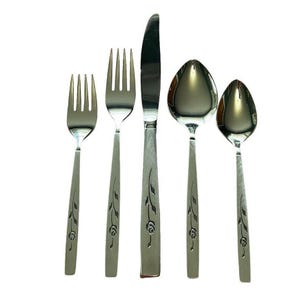 Peut inclure: Un ensemble de couverts en acier inoxydable comprenant un couteau, deux fourchettes et deux cuillères. Chaque pièce présente un motif floral sur le manche. L'ensemble est présenté sur fond blanc, mettant en valeur les surfaces polies et réfléchissantes.