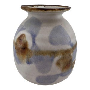 Può includere: Un vaso in ceramica bianca con corpo arrotondato e bordo marrone. Il vaso è decorato con un motivo astratto blu e marrone.