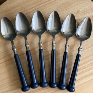 Könnte beinhalten: Sechser-Set silberne Löffel mit blauen Griffen. Die Löffel haben ein traditionelles Design und sind perfekt für den täglichen Gebrauch.