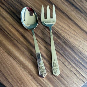 May include: A silver serving set with a spoon and fork. The handles have a decorative design.