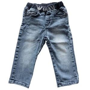 Puede incluir: Pantalones vaqueros azul claro con cintura elástica azul oscuro. La cintura lleva el nombre de la marca "ARMANI" en letras blancas. Los pantalones tienen un diseño clásico de cinco bolsillos y son adecuados para niños.