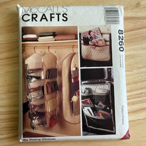Puede incluir: Sobre de patrones McCall's Crafts con imágenes de organizadores de armario y soluciones de almacenamiento. El sobre incluye el número 8260 y el texto "One Envelope" y "Pattern/Patron". El patrón es de Nancy Zieman.