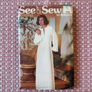 Op de afbeelding: Een vintage "See & Sew" naaipatroon van Butterick. De patroonhoes toont een vrouw in een lange, witte jurk met klokmouwen. De jurk heeft een knoopsluiting aan de voorkant. De hoes toont ook een rieten stoel en patroonnummer 5796.