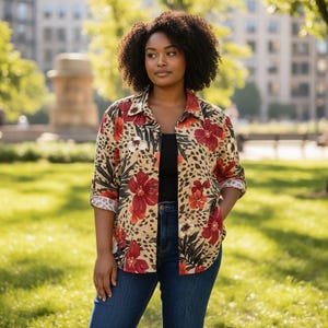 May include: A button-down shirt with a beige leopard print background and large red floral designs. The shirt has rolled-up sleeves and is paired with dark blue jeans. The shirt is open, revealing a black top underneath.