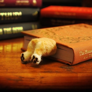 May include: A brown book with gold lettering that reads "The Hound of the Baskervilles and The Valley of Fear" with a felt dog bookmark sticking out of the top.