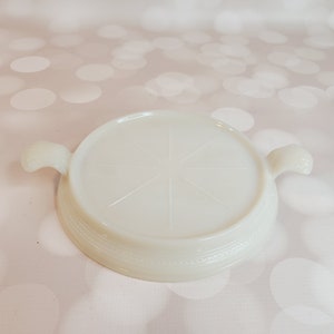 Puede incluir: Posavasos de vidrio blanco lechoso con dos asas. El posavasos tiene un diseño de estrella en relieve en el centro.