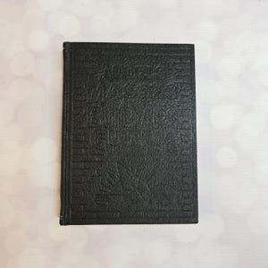 Puede incluir: Un libro de tapa dura negro titulado "Model Builders Guide" con texto en relieve y una cubierta texturizada. El libro está cerrado y tiene un borde dorado. El libro es una guía para modelistas.