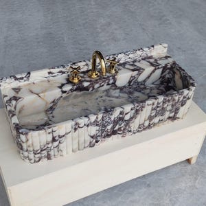 Elegant sink made of Calacatta Viola marble, highlighting dramatic veining and a smooth honed finish for a luxurious touch.