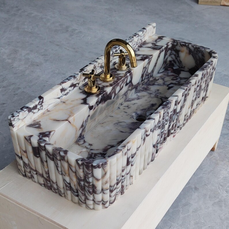 Custom Calacatta Viola marble sink with no faucet holes, designed for seamless integration with wall-mounted fixtures.